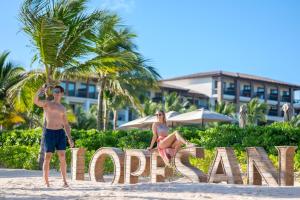 蓬塔卡纳Lopesan Costa Bávaro Resort, Spa & Casino的坐在海滩上标牌上的男女