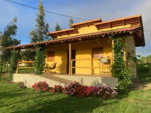 巴纳内拉斯Chalés Samambaia的前面有鲜花的黄色房子