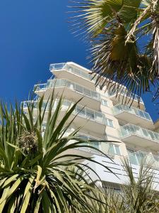 利多迪耶索罗Hotel Nizza Frontemare Superior 3 Stelle的一座高大的白色建筑,前面有棕榈树