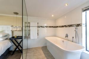 开普敦The Jewel B&B的白色的浴室设有浴缸和床。