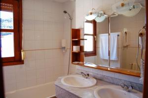 特拉加塞特埃尔加莫酒店的浴室设有2个水槽、镜子和浴缸。