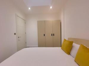 米尔顿凯恩斯Lovely 2 Double Bedroom Flat with free parking - At the Atrium MK的卧室配有一张带黄色枕头的大型白色床。