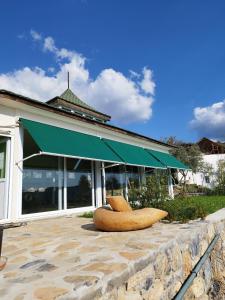 米拉斯Olive Garden Retreat的一座带绿色遮阳篷和两把椅子的建筑
