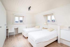 克诺克－海斯特CAPRINO Guesthouse的白色客房的两张床、书桌和窗户
