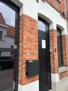 鲁汶Escape in Leuven - Self check in的砖砌建筑上一扇带窗户的黑色门