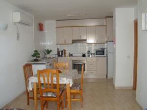 萨洛Apartamento Cap de Salou的厨房配有桌子、一些椅子、桌子和桌子。