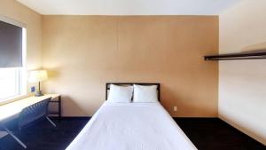 渥太华公寓及会议中心 - 渥太华西部的一间卧室配有一张带白色床单的床和一扇窗户。