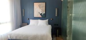 特拉维夫SeaNet Hotel By AFI Hotels的卧室配有白色的床和蓝色的墙壁