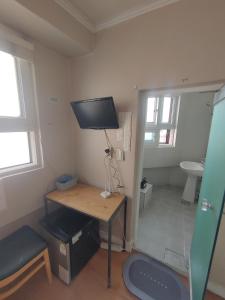 首尔Joy Guesthouse的小房间设有一张桌子和一台墙上的电视
