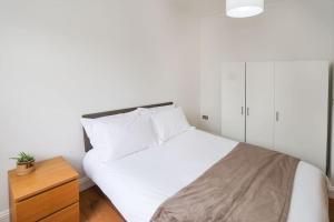 伦敦Comfy 1 bed flat in Tufnell Park的卧室配有白色的床和木制梳妆台。