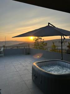 米德希特本-古里安נס הבריאה的一个带遮阳伞的热水浴池,享有日落美景