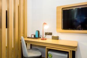 伊凯贾Ivy Hotel Emerald的客房设有一张桌子、一台电视和一把椅子