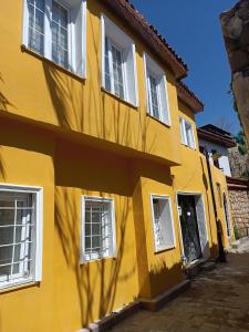 安塔利亚TAG Pansiyon的黄色的建筑,有白色的窗户和门