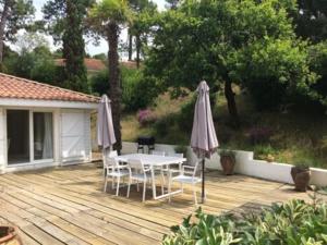 卡布勒通BRUYERES - Capbreton, belle villa spacieuse entre ville et plages au calme的庭院配有桌椅和遮阳伞。