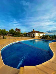 奥尔纳丘埃洛斯Casa Rural Mirador de la Alcaidía的一座大型蓝色游泳池,后面有一座房子