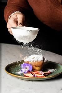 罗马罗马科索里亚斯特美居酒店的把糖粉洒在盘子上的糕点上的人