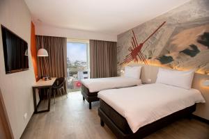 利马ibis Styles Lima Benavides Miraflores的酒店客房配有两张床和一张书桌