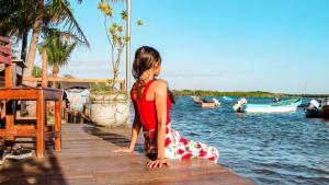 拉斯彭尼塔斯Hotel Restaurante Spa La Barca de Oro的坐在水边码头上的年轻女孩
