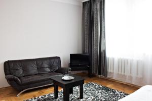 KonopnitsaHotel Sofiivka的客厅配有黑色真皮沙发和桌子
