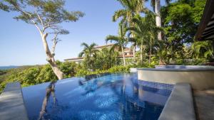 巴希利托Villa Zindagi Luxury Villa Private Pool - Reserva Conchal的棕榈树度假村内的游泳池