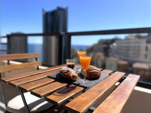 博索莱伊NEW Studio, piscine et vue mer • proche de Monaco的一张木桌,上面放着两块糕点和一杯橙汁