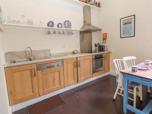 基尔拉什The Merchant's House的厨房配有木制橱柜、水槽和桌子