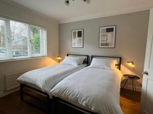 贝弗利Stunning Beverley Bungalow w Fireplace, private parking, and garden的一间卧室配有两张带白色床单和两盏灯的床。