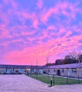 布拉克利Briary Cottages at Iletts Farm的粉红色天空的建筑上方的日落