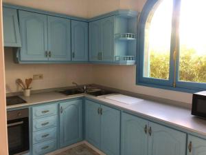 皮莱斯Villa Azul Beach的厨房配有蓝色橱柜和窗户。
