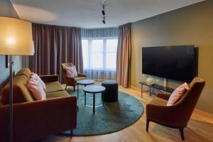 厄勒布鲁斯堪迪克大酒店的客厅配有沙发、椅子和平面电视。
