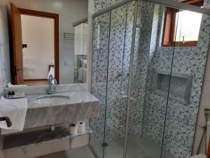 卡皮托利乌Pousada Cheiro da Terra的一间带水槽和玻璃淋浴的浴室