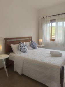 卡皮托利乌Pousada Cheiro da Terra的卧室配有一张带枕头的大型白色床。