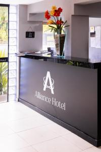 巴乌鲁Alliance Hotel的在一个合作酒店,在柜台上花的标志