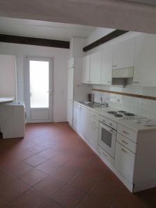 阿斯科纳卡萨索特阿尔萨斯公寓的厨房配有白色橱柜和红色瓷砖地板。
