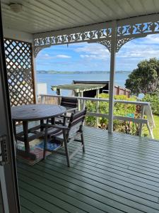 旺阿雷Tamaterau Seaview House in Whangarei的木甲板,配有桌子和野餐桌