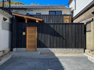 仓敷Temari Inn Madoromi的房屋前有木门的黑色围栏