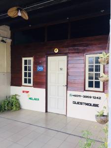 马六甲Stop @Melaka Guesthouse的一座带白色门和2扇窗户的木制建筑