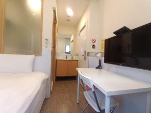 台北卡乐町旅店 的客房设有床、书桌和电视。