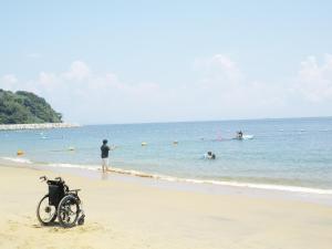 Utsumiサポートイン南知多的一辆摩托车停在海滩上,人们在水中