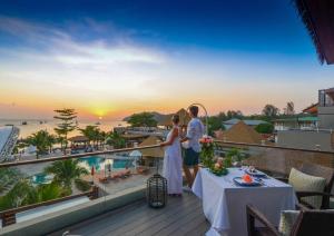 丽贝岛Ananya Lipe Resort的一对夫妇站在阳台上欣赏日落美景