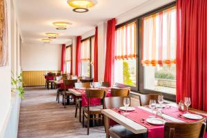 DeudesfeldPension Haus Anny的一间带桌椅和红色窗帘的餐厅