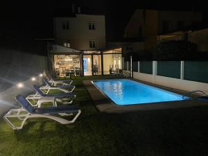 梅利德Pension San Anton的夜间在房子旁边设有躺椅的游泳池