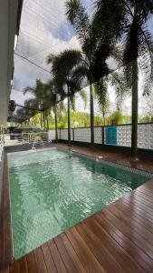 SunggalSaka Hotel Medan的一座棕榈树游泳池和一个木甲板