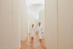 黄金海岸黄金海岸RACV皇家松林度假村的穿着白色长袍的两名妇女走下走廊