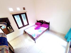 DemanganKotagede Street Homestay Jogja的一间卧室配有一张带紫色枕头的床