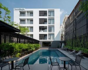 曼谷Lilit Bang Lumphu Hotel的大楼前的带桌椅的游泳池