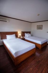 万象老挝兰花酒店 的铺有木地板的客房内的两张床