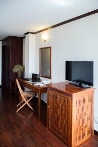 万象老挝兰花酒店 的客房设有一张桌子和一台平面电视