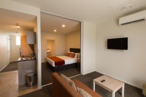 基督城Ramada Suites by Wyndham Christchurch City的酒店客房,配有床和电视