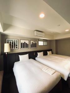 京都京都糸屋酒店的配有白色床单的客房内的两张床